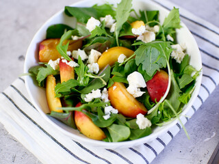 Light salad of rukolla, peaches and cheese on concrete background. top veiw. Diet food.