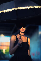 Goth ballerina holding parasol and wearing sunglasses posing in abandoned building