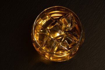  liquor glasses of whiskey, rum, etc., lit liquor from inside glass with ice cubes tray or slate stone plate with text space