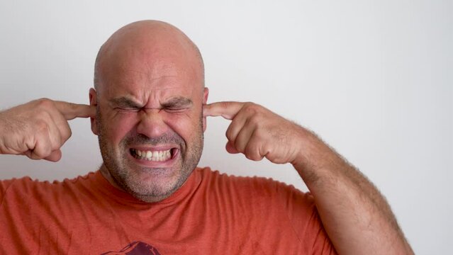 Close up, a man covers his ears with his fingers so as not to hear an explosion