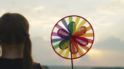 happy child with spinner toy sunset background. girl childhood dream. child park with windmill....