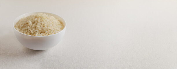 Dry camollino rice in a white ceramic bowl on a light background. The concept of vegetarian food. Healthy Eating. Banner. Copy space.