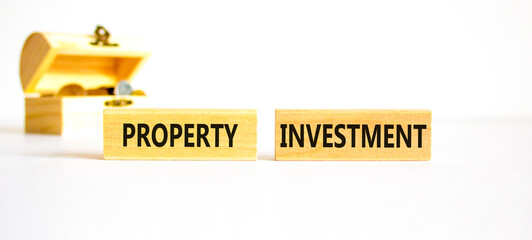 Property investment symbol. Concept words Property investment on wooden blocks on a beautiful white table white background. Wooden chest with coins. Business Property investment concept. Copy space.