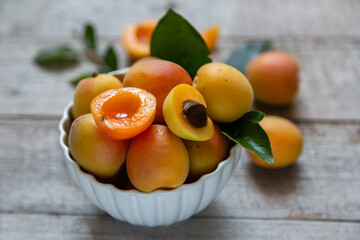 Ripe juicy apricots in a white bowl on a wooden background