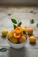 Ripe juicy apricots in a white bowl on a wooden background