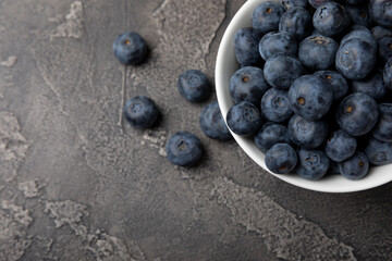 Blueberries in a ceramic bowl on a black textured background. Ripe and fresh blueberries. Vitamins. Healthy food. Juicy berry.Copy space.Place for text