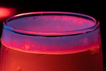 macro photo of white beer foam in a glass. red lights and black background 
