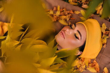 a beautiful brunette with makeup in a yellow beret and yellow jacket walks in the park in autumn.