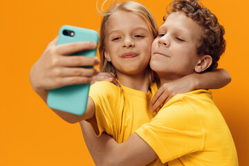 beautiful, funny girl and boy stand in yellow clothes and take a selfie on a smartphone, hugging each other