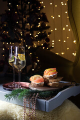 Christmas champagne with red fish appetizer and Christmas tree in sparkling lanterns