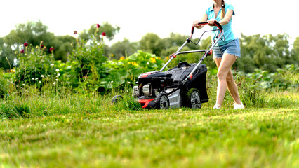 a girl mows the lawn with a lawn mower