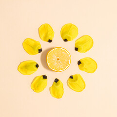 Creative lemon with flower petals on beige background. Summer flat lay concept