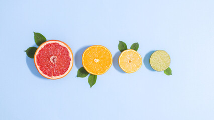 Creative blue background with sliced citrus fruits with green leaves. Flat lay summer tropical concept