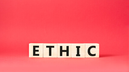 Ethic symbol. Wooden cubes with word Ethic. Beautiful red background. Ethic concept. Copy space.