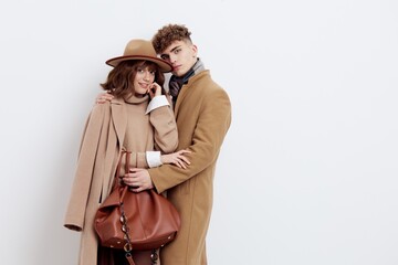horizontal photo of a sweet, loving couple in autumn clothes standing on a white background gently embracing each other
