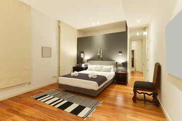 Bedroom decorated in classic vintage style with gray walls, matching headboard and cushions, wooden chairs, rug and solid wood nightstands
