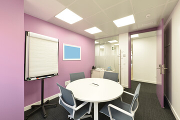 Small office cubicle with a round boardroom table with matching chairs and a presentation lectern