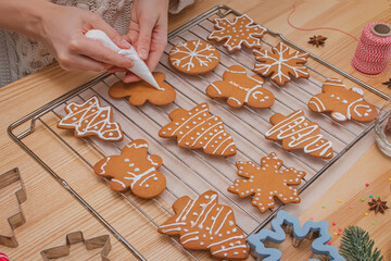 Woman's hands decorating homemade Christmas gingerbread cookies