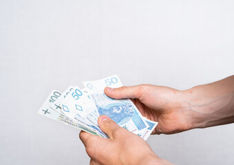 The man holds Polish zlotys in banknotes. Concept showing polish economy, finance and policy. Rising inflation in Poland. 