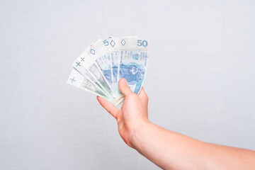 close-up of 100 and 50 zloty banknotes held in the hand on a light background - obrazy, fototapety, plakaty