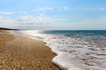 Seascape. Wild beach and calm sea close-up. Selective narrow focus at the water's edge
