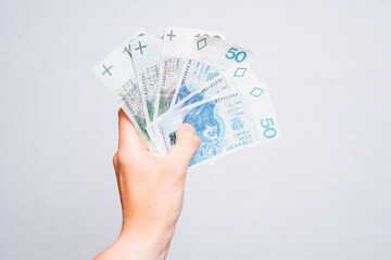close-up of 100 and 50 zloty banknotes held in the hand on a light background