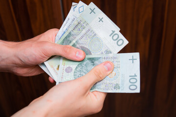 The man holds Polish zlotys in banknotes. Concept showing polish economy, finance and policy. Rising inflation in Poland. 