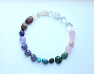 The circle is lined with natural minerals. Semi-precious stones of different colors are processed. Amethyst, rose quartz, rock crystal and apatite. Frame of precious stones on a white background.