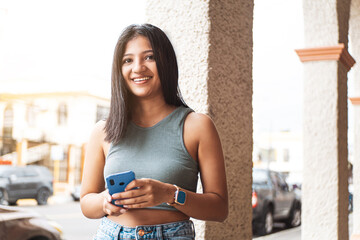 Young latin american young woman using a mobile looking away.