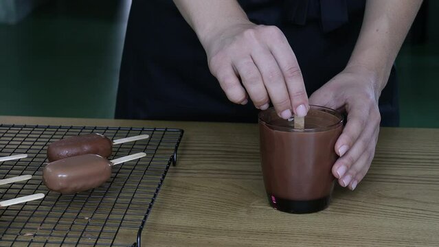  A pastry chef dips a popsicle in chocolate. Close-up. The process of making desserts. High quality 4k footage