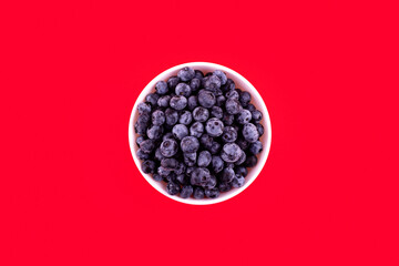 Top view of fresh juicy ripe blueberries in bowl isolated on red. Flat lay copy space. Healthy berry, organic food, antioxidant, vitamin, blue food. Blueberry pattern