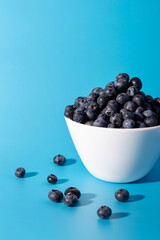 Beautiful fresh blueberries in a white bowl on a blue background.Vegan and vegetarian concept. Summer healthy food.