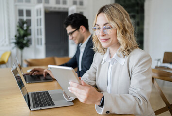 Obraz premium Two Creative Managers, a woman and a man, are working on a new Startup project in the office, using Laptops