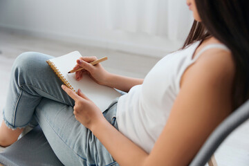 Obraz premium Top view of hand young brunette holds pen and notebook in home interior. Writer concept. Copy space Offer Banner. Closeup shot
