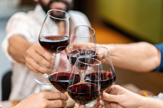 leisure, people and celebration concept - close up of happy friends drinking red wine and toasting at restaurant or pub