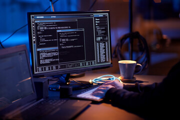 cybercrime, hacking and technology concept - close up of hacker in dark room writing code or using...