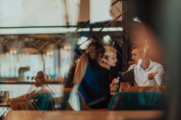 Happy businesspeople smiling cheerfully during a meeting in a coffee shop. Group of successful business professionals working as a team in a multicultural workplace.