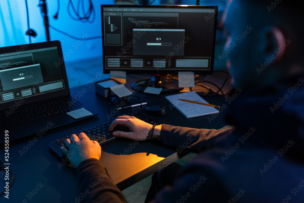Poster cybercrime, hacking and technology concept - close up of male hacker in dark room writing code or us