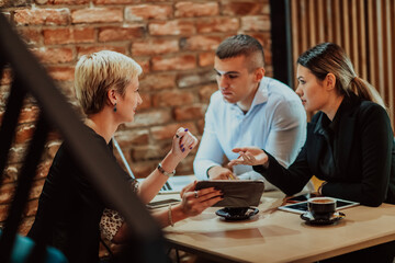 Happy businesspeople smiling cheerfully during a meeting in a coffee shop. Group of successful business professionals working as a team in a multicultural workplace.