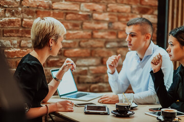 Happy businesspeople smiling cheerfully during a meeting in a coffee shop. Group of successful business professionals working as a team in a multicultural workplace.