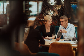 Happy businesspeople smiling cheerfully during a meeting in a coffee shop. Group of successful business professionals working as a team in a multicultural workplace.