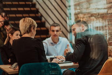 Happy businesspeople smiling cheerfully during a meeting in a coffee shop. Group of successful business professionals working as a team in a multicultural workplace.