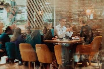 Happy businesspeople smiling cheerfully during a meeting in a coffee shop. Group of successful business professionals working as a team in a multicultural workplace.
