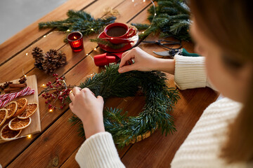winter holidays, diy and hobby concept - close up of woman with fir branches making christmas wreath at home © Syda Productions