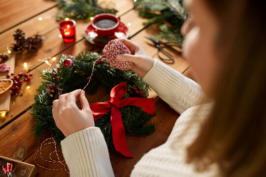 winter holidays, diy and hobby concept - close up of woman with decorative rope making christmas wreath at home