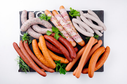 Traditional raw grill platter with different types of bratwursts prepared for a summer barbecue offered as a top view on a rustic board