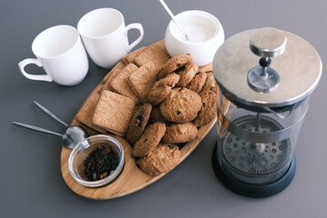 A tasty snack two cups of black tea and a plate of oatmeal cookies a wooden board on the gray background, leaf tea.