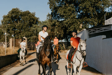several young riders riding horses through the streets of a housing estate