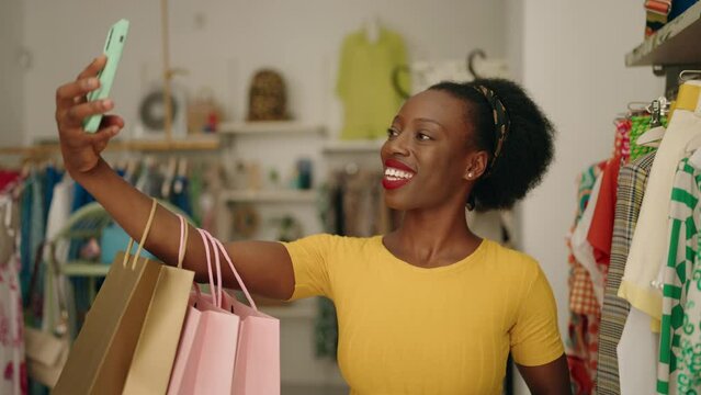 African american woman customer holding shopping bags make selfie by smartphone at clothing store