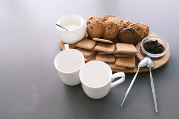 A tasty snack two cups of black tea and a plate of oatmeal cookies a wooden board on the gray background, leaf tea.